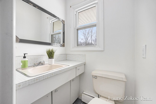 bathroom featuring baseboard heating, toilet, vanity, and decorative backsplash