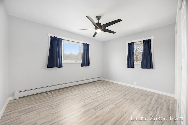 unfurnished room featuring a wealth of natural light, wood finished floors, baseboards, and a baseboard radiator