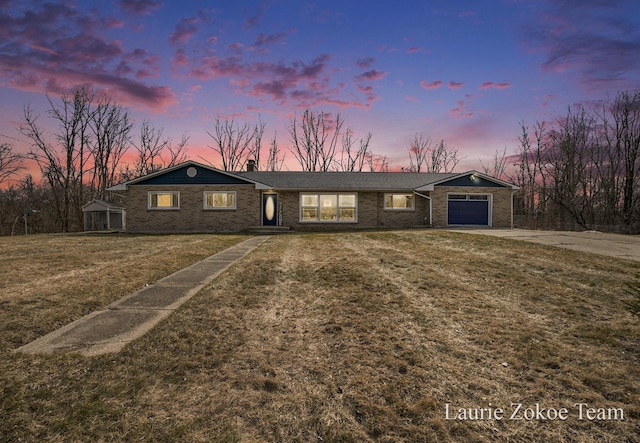 view of front of house featuring a front lawn, an attached garage, brick siding, and driveway