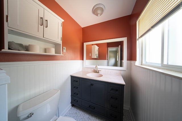 bathroom featuring vanity, toilet, and a wainscoted wall