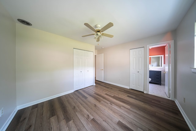 unfurnished bedroom featuring visible vents, ensuite bathroom, baseboards, and dark wood-style flooring