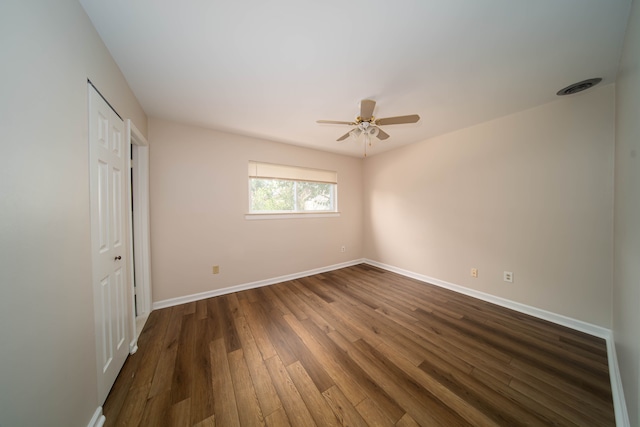 unfurnished room featuring visible vents, baseboards, dark wood-type flooring, and ceiling fan