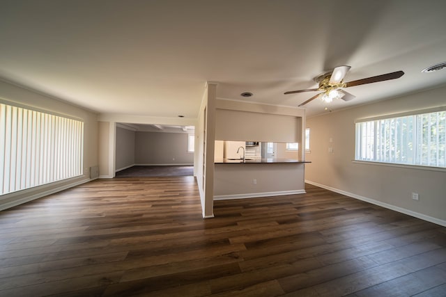 unfurnished living room with a ceiling fan, baseboards, visible vents, dark wood finished floors, and a sink