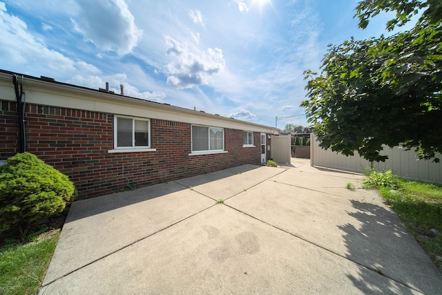 exterior space featuring brick siding, a patio area, and fence