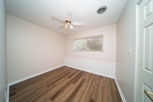 empty room featuring visible vents, baseboards, ceiling fan, dark wood finished floors, and wainscoting