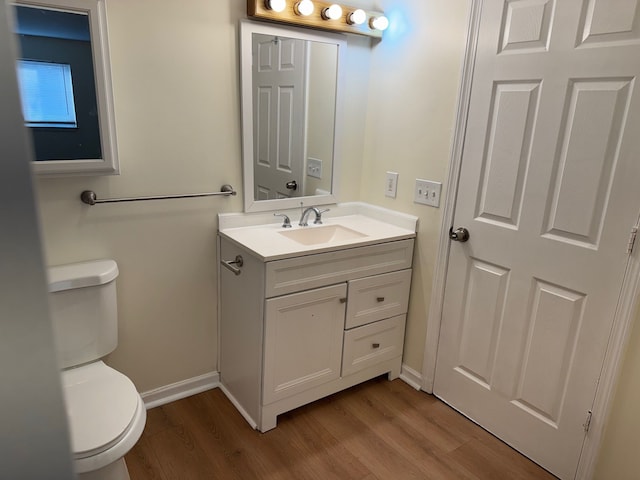 half bathroom featuring toilet, vanity, and wood finished floors