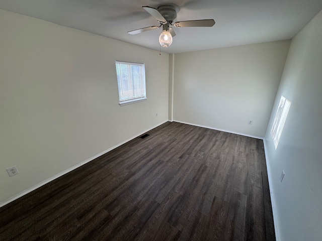 spare room featuring dark wood finished floors, visible vents, baseboards, and ceiling fan