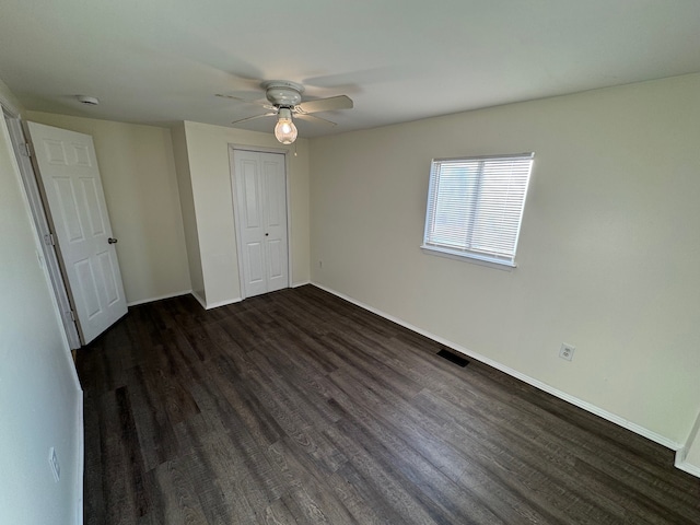 unfurnished bedroom featuring visible vents, ceiling fan, baseboards, a closet, and dark wood-style floors