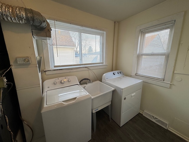 clothes washing area with visible vents, dark wood-type flooring, washing machine and dryer, laundry area, and a sink