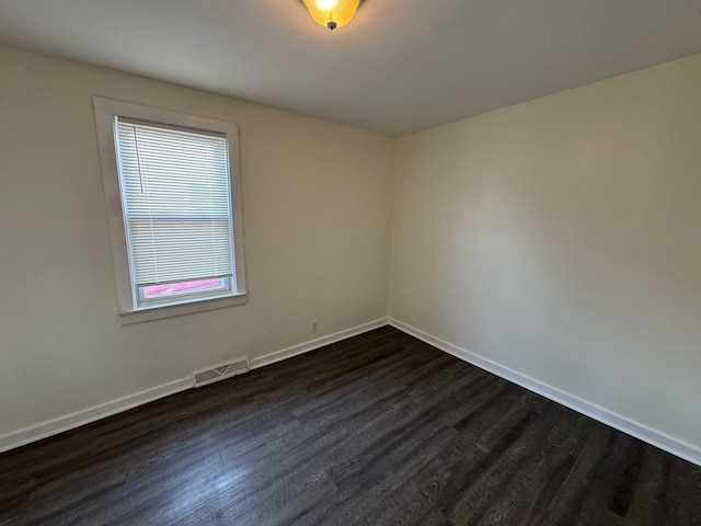 spare room with visible vents, baseboards, and dark wood-style floors