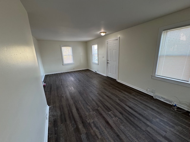 unfurnished room with baseboards, visible vents, and dark wood-style flooring