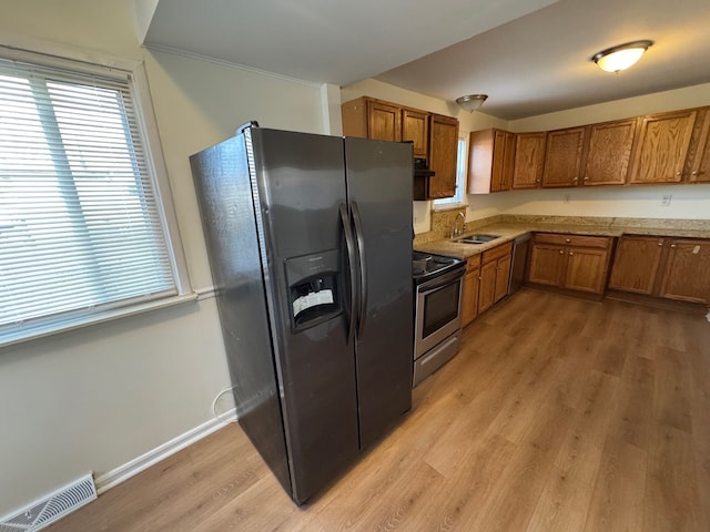 kitchen with visible vents, a sink, stainless steel electric range, brown cabinetry, and black refrigerator with ice dispenser