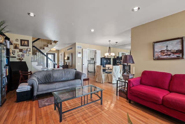 living room with a chandelier, stairway, visible vents, and wood-type flooring