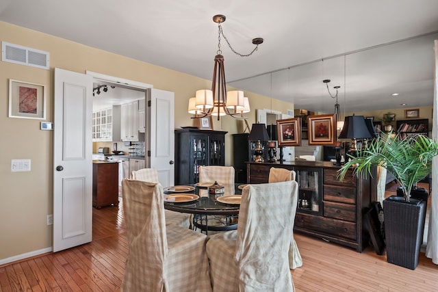 dining area with visible vents, an inviting chandelier, baseboards, and light wood-style floors