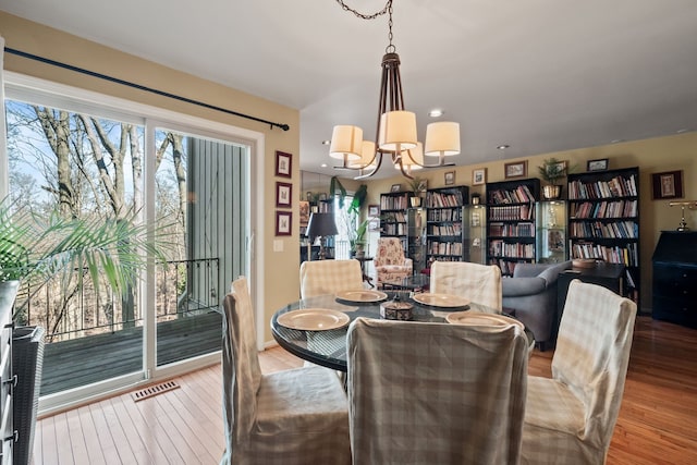 dining area with visible vents, a notable chandelier, and wood finished floors