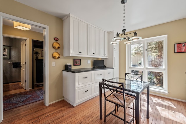 dining area with a notable chandelier, baseboards, and light wood-style floors