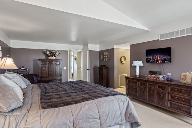 bedroom with vaulted ceiling, light colored carpet, and visible vents