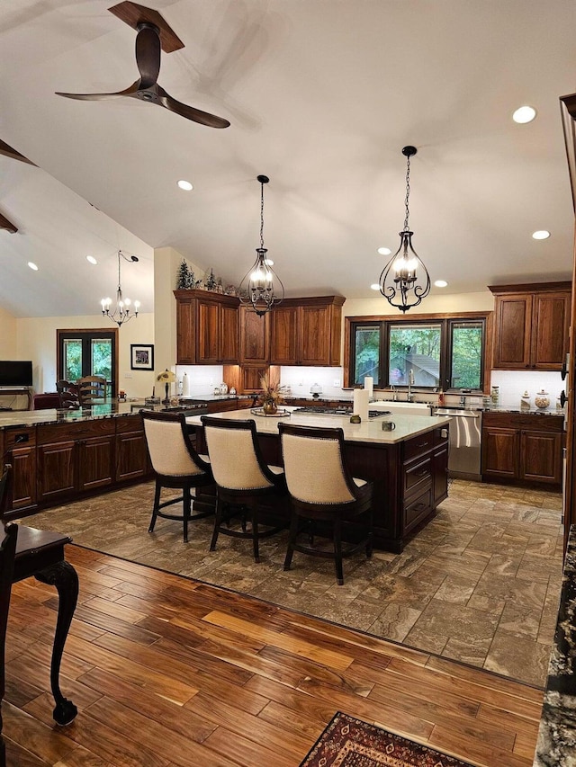 kitchen with stainless steel dishwasher, vaulted ceiling, dark wood-style floors, and pendant lighting