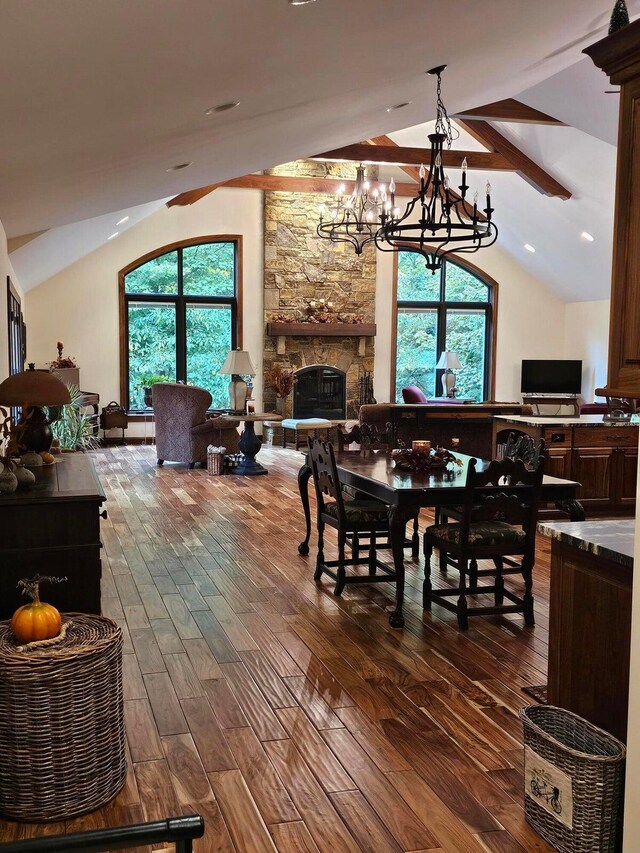 dining area with dark wood-type flooring, a stone fireplace, and vaulted ceiling with beams