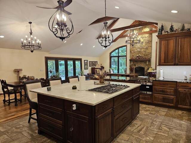 kitchen with stone finish floor, stainless steel gas cooktop, a breakfast bar area, light countertops, and vaulted ceiling