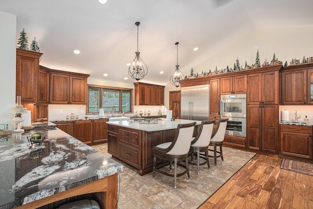 kitchen featuring a center island, a sink, a kitchen breakfast bar, vaulted ceiling, and stainless steel appliances