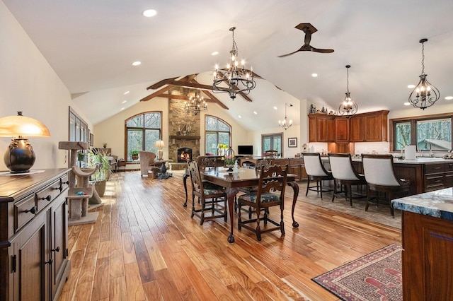 dining space featuring an inviting chandelier, a fireplace, recessed lighting, high vaulted ceiling, and light wood finished floors