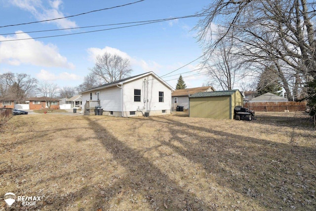 rear view of property with a shed, an outdoor structure, and fence