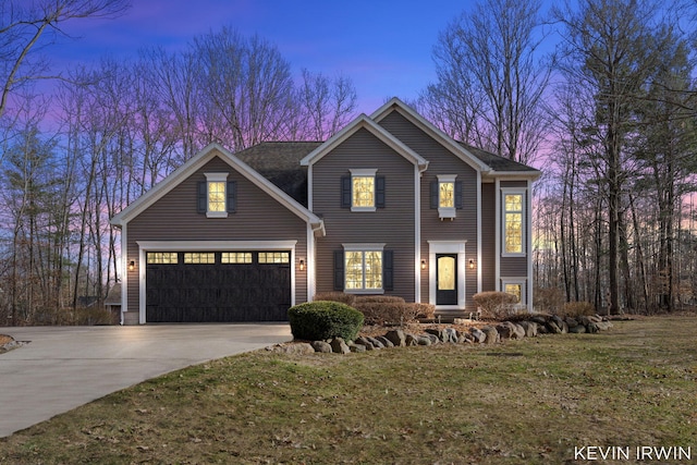 view of front of house with an attached garage, concrete driveway, and a yard