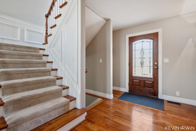 foyer with visible vents, baseboards, wood finished floors, and stairs