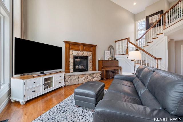 living room featuring recessed lighting, stairway, a stone fireplace, light wood finished floors, and baseboards