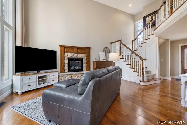 living room with stairway, baseboards, a towering ceiling, and wood finished floors