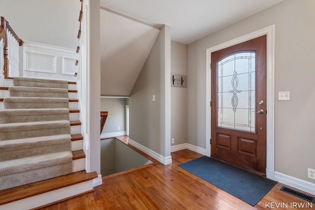 entrance foyer with stairs, wood finished floors, visible vents, and baseboards