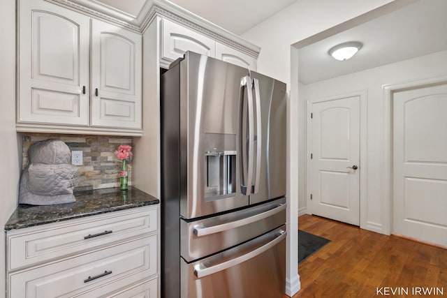 kitchen featuring tasteful backsplash, stainless steel fridge, wood finished floors, and dark stone countertops