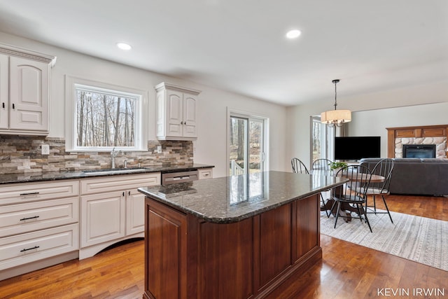 kitchen with dishwasher, tasteful backsplash, light wood finished floors, and a sink