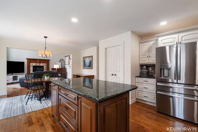 kitchen featuring dark wood finished floors, dark stone countertops, stainless steel fridge with ice dispenser, and white cabinetry