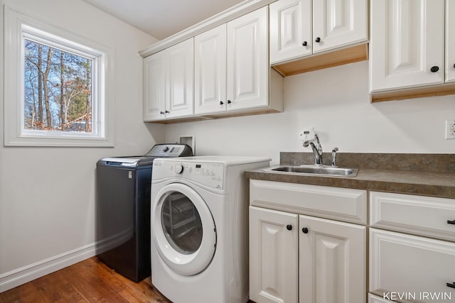 laundry room featuring a sink, washing machine and dryer, wood finished floors, cabinet space, and baseboards