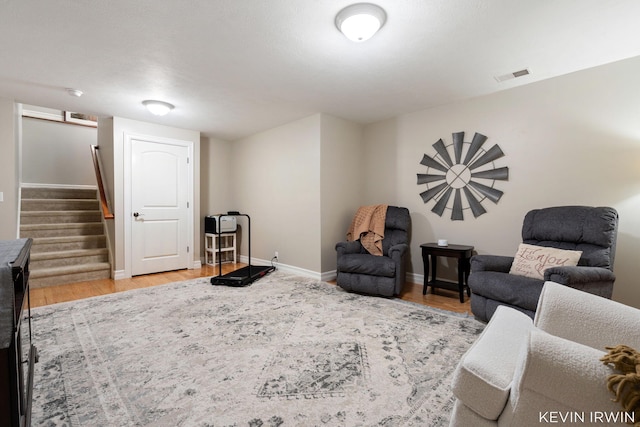 living area featuring visible vents, stairway, light wood-type flooring, and baseboards