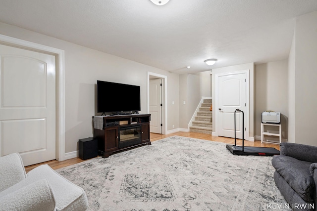 living room with stairway, baseboards, and light wood-style floors