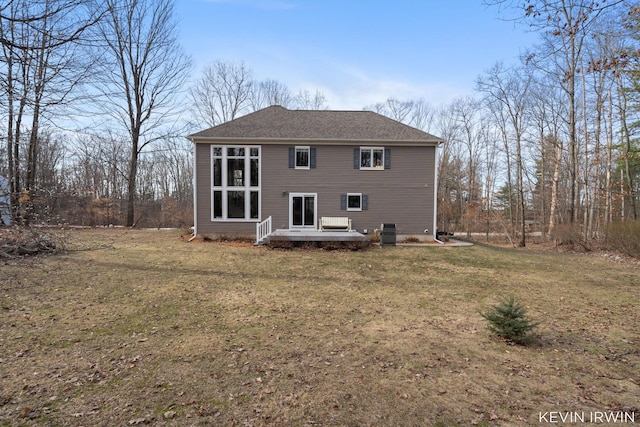 back of property with a yard, central AC unit, and a shingled roof