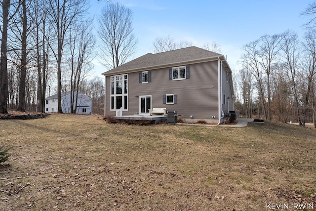 back of property with central air condition unit, a lawn, and a shingled roof