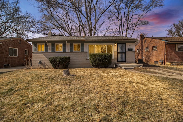 ranch-style home with a front yard, brick siding, and a chimney