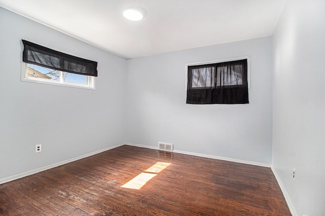 empty room featuring visible vents, baseboards, and wood finished floors