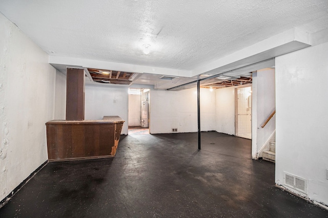 finished below grade area with stairs, visible vents, water heater, and a textured ceiling