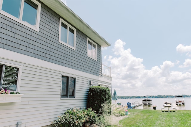 view of side of home featuring a yard and a water view