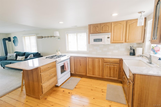 kitchen featuring decorative backsplash, white appliances, light wood-type flooring, and a peninsula