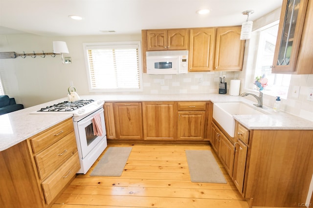 kitchen featuring a sink, decorative backsplash, white appliances, and plenty of natural light