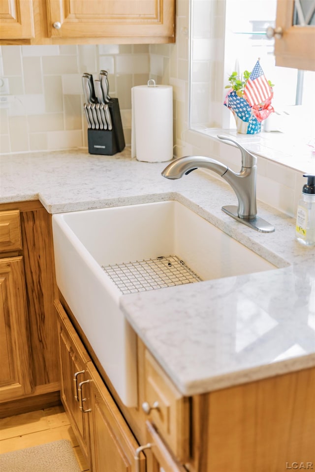 interior details with tasteful backsplash, brown cabinets, and light stone countertops