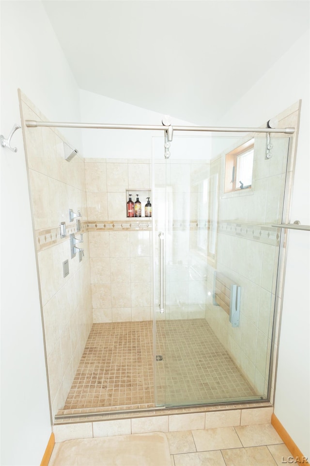 full bathroom with tile patterned flooring, a shower stall, and lofted ceiling