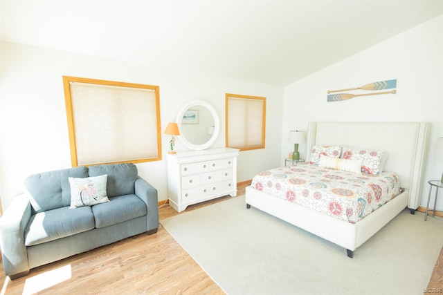 bedroom featuring baseboards, wood finished floors, and vaulted ceiling