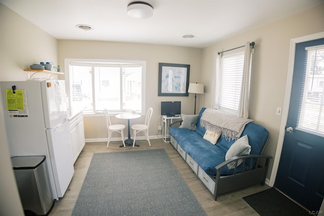 living area with light wood finished floors, visible vents, and baseboards